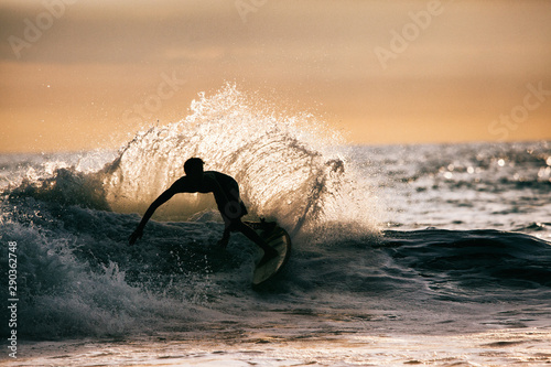 Sunset Surf - Silhouette of Young Male Surfer Creating Big Splas photo