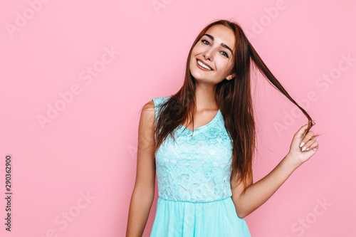 young girl, in a bright dress, smiling and posing on a pink background