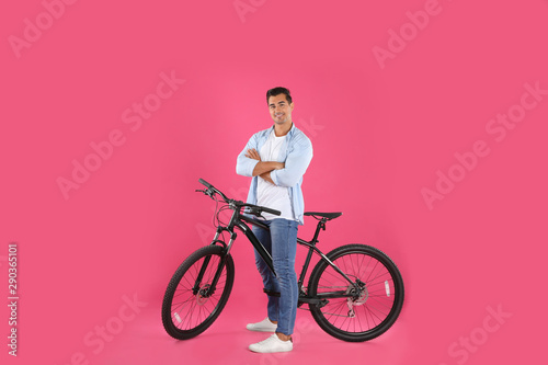 Handsome young man with modern bicycle on pink background © New Africa
