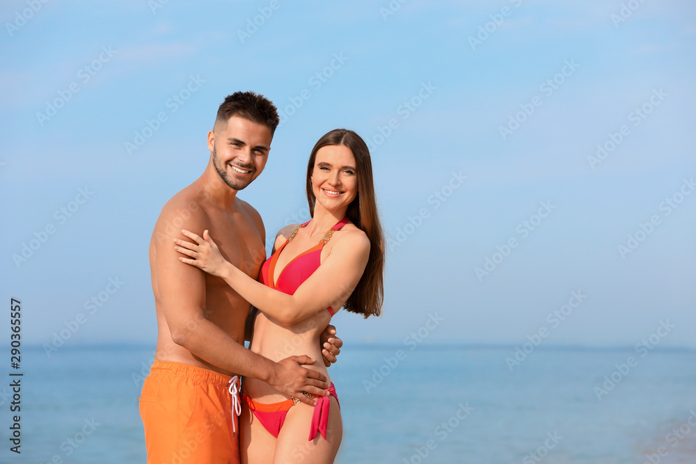 Young woman in bikini with her boyfriend on beach, space for text. Lovely couple Young woman in bikini with her boyfriend on beach, space for text. Lovely couple