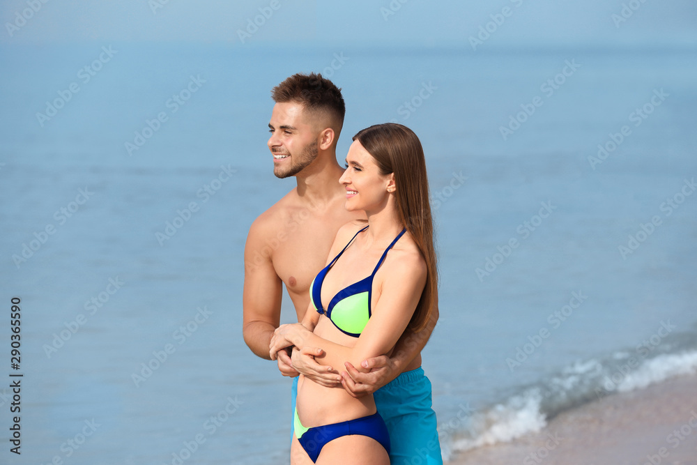 Young woman in bikini with her boyfriend on beach. Lovely couple Young woman in bikini with her boyfriend on beach. Lovely couple