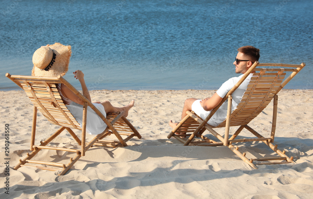 Young couple relaxing in deck chairs on beach