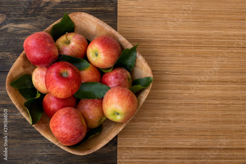 Ripe red and pink apples on wooden background. Apples in bowl. From above. Copy space