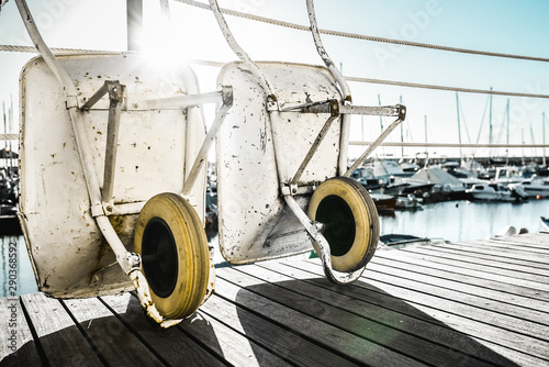 Two wheelbarrows leaning against a fence in a harbour environment photo