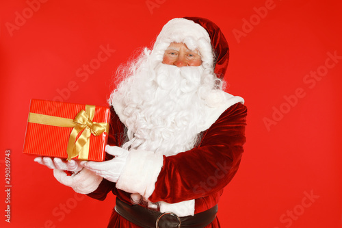 Authentic Santa Claus with gift box on red background
