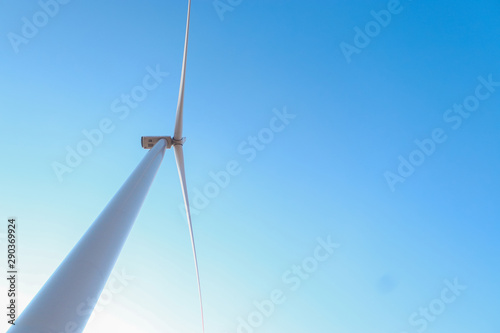 Looking upward to a big wind turbine and a blue sky. Alternative energy source, production and power generation. Ecology and freedom concept © Oleksandra