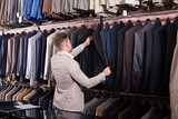 interested male customer examining men’s suits