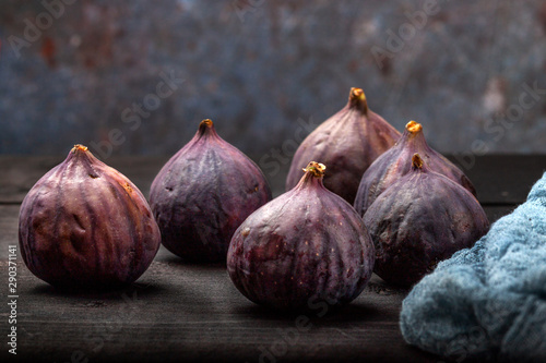 Fresh figs lie on a black wooden table. Beautiful blue fig fruits close up