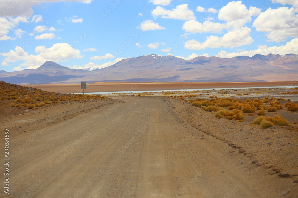 Valley in the Bolivia desert with a dusty road crossing the dried vegetation. Off road trail with 4x4 vehicles