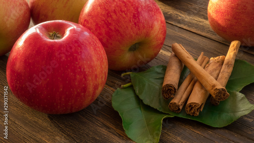 Raw red and green apples with cinnamon sticks on darek  wooden table, top view.  Close up photo