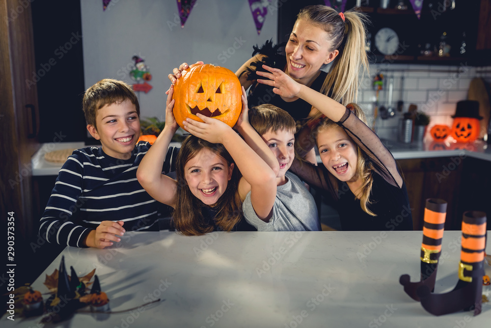 Cheerful children with mother holding Jack-o-lantern preparing for Halloween party, laughing Cheerful children with mother holding Jack-o-lantern preparing for Halloween party, laughing