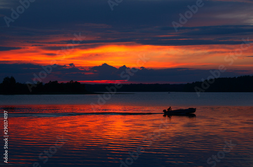 Lonely boat dissecting lake calm waters at sunset light