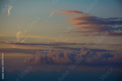 Nubi al tramonto che si colorano di rosso e si intrecciano con le scie degli aerei photo