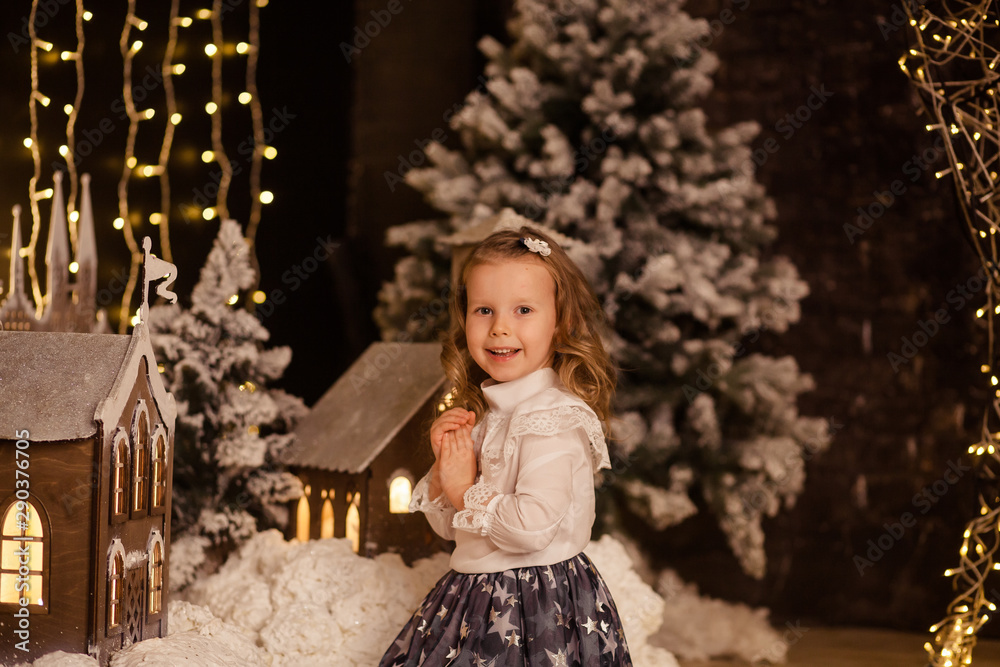 portrait of a happy cute girl of 4-5 years old in the New Year’s interior, waiting for a happy Christmas holiday