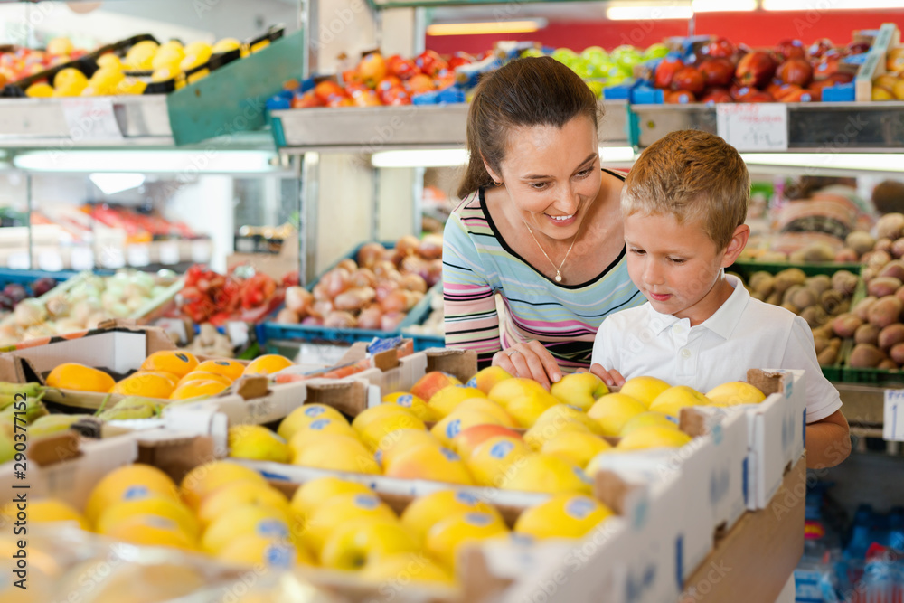 Cheerful mother with little boy buying pears and apples at store