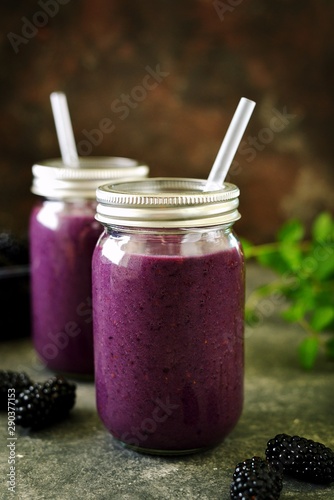 Healthy blackberry organic smoothie with natural yogurt and honey in a glass jar on an old wooden background.