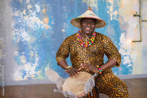 Handsome african drummer weared in traditional costume playing on djembe drum