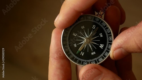 Male hands hold the compass and set needle to the north. Checking direction with a compass in hands. Close up shot of a spinning vintage compass.
