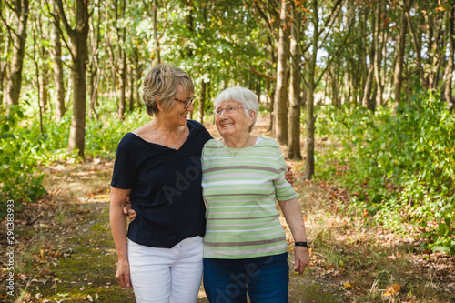 Senior lady with her aged mother with dementia, embracing and smiling in a summer park photo