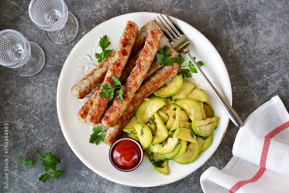 Grilled chicken sausages with zucchini salad in olive oil, soy sauce, wine vinegar, garlic and cilantro. Top view. 