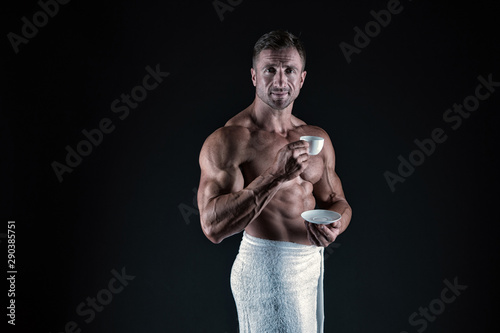 Coffee enhances athletic performance. Athletic man with fit torso drink coffee afther bath. Sexy bodybuilder hold coffee cup on black background. Black coffee gives you more energy, vintage filter photo