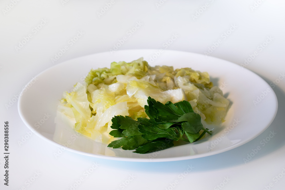 Stewed cabbage with parsley on a white plate
