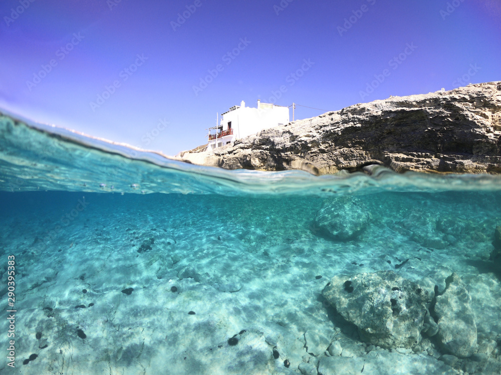 Above and below underwater photo of crystal clear turquoise sea paradise beach of Ammos and main town - port of Koufonisi island, Small Cyclades, Greece