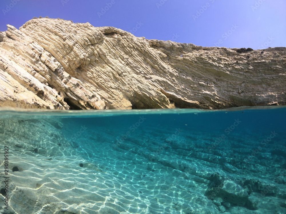 Fototapeta premium Above and below underwater photo of crystal clear sea paradise rocky seascape of Laki beach in Kato Koufonisi island, Cyclades, Greece