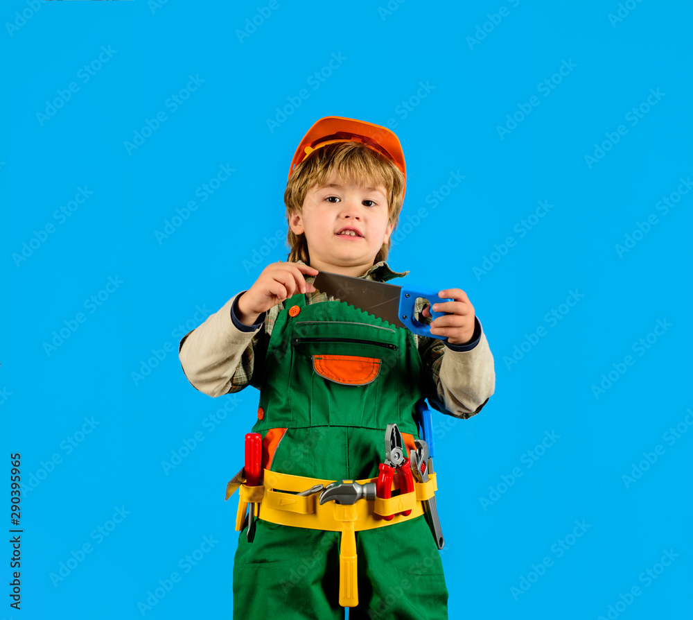 Tools for building. Little kid repairman with with saw. Little boy in builder's uniform tool belt. Builder boy in helmet and tools. Child game. Work with tools. Repair. Kid boy as builder or repairer.