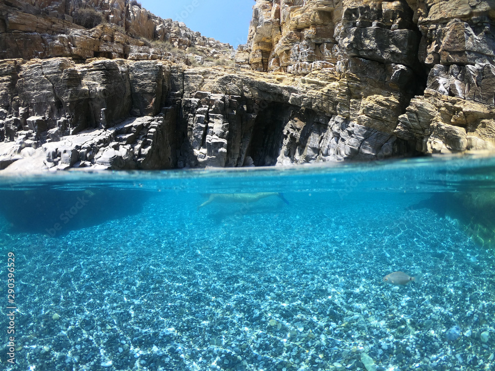 Above and below underwater photo of crystal clear sea paradise rocky seascape full of caves beach of Mouros, Amorgos island, Cyclades, Greece Above and below underwater photo of crystal clear sea paradise rocky seascape full of caves beach of Mouros, Amorgos island, Cyclades, Greece