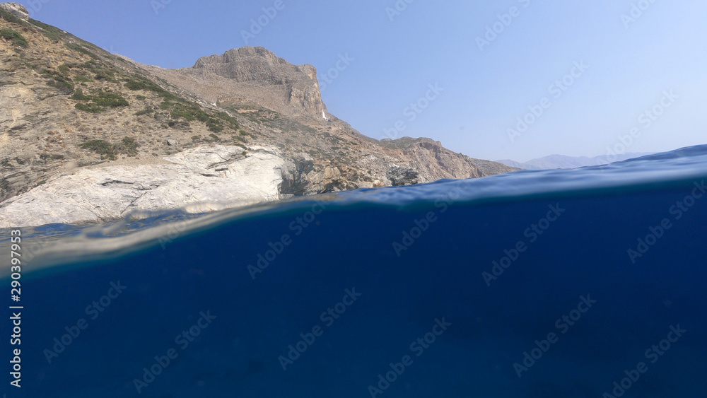 Above and below underwater photo of crystal clear sea paradise rocky seascape and small chapel of Agia Anna just next to iconic Hozoviotissa Monastery, Amorgos island, Cyclades, Greece Above and below underwater photo of crystal clear sea paradise rocky seascape and small chapel of Agia Anna just next to iconic Hozoviotissa Monastery, Amorgos island, Cyclades, Greece