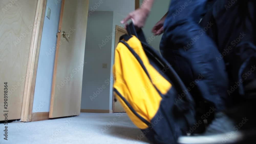 Low angle, male packs backpack and leaves room Low angle, male packs backpack and leaves room