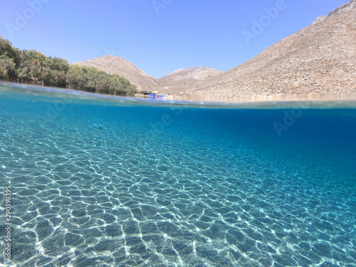 Above and below underwater photo of crystal clear turquoise beach of Kaminakia, Astypalaia island, Dodecanese, Greece