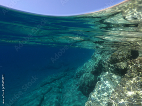 Above and below underwater photo of crystal clear sea paradise rocky seascape of Laki beach in Kato Koufonisi island, Cyclades, Greece © aerial-drone