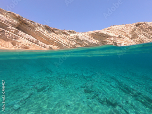 Above and below underwater photo of crystal clear sea paradise rocky seascape of Laki beach in Kato Koufonisi island, Cyclades, Greece
