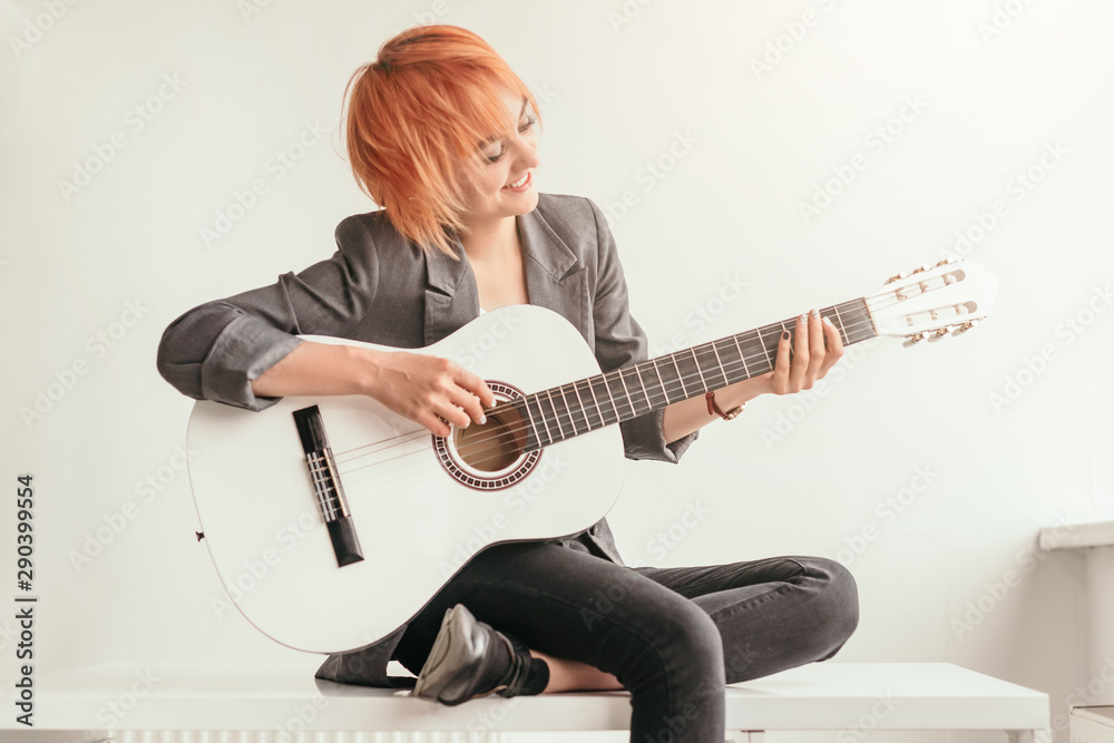 Smiling female playing guitar on bench Smiling female playing guitar on bench