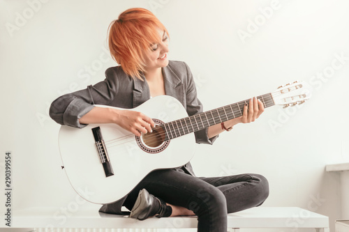 Smiling female playing guitar on bench