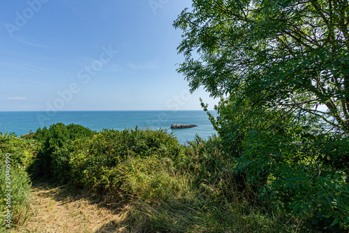 A panorama seascape view with rocky island along the coast under a majestic blue sky and some white clouds