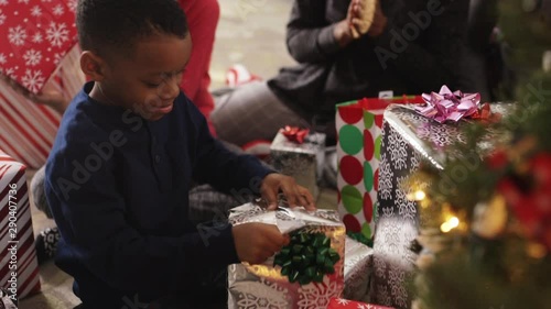 Black family watching boy open gift on Christmas morning