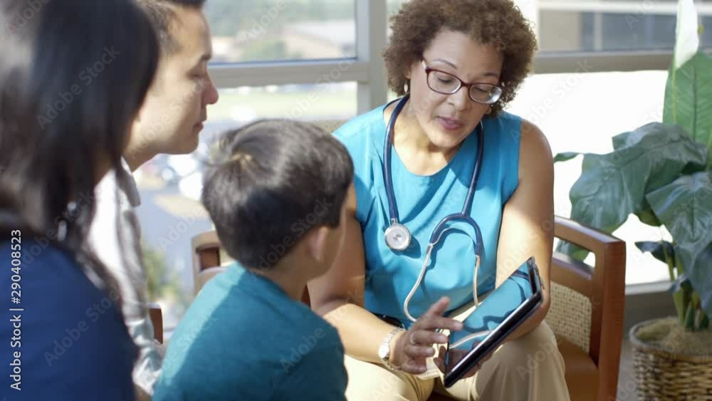 Doctor with digital tablet talking to family in hospital lobby