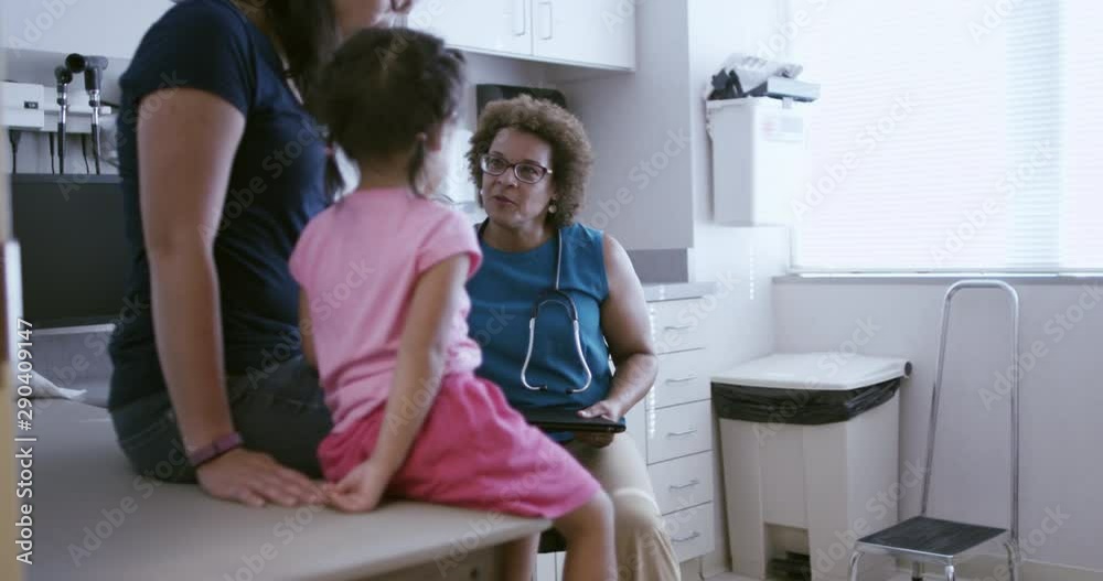 Pediatrician talking to mother and daughter in examination room Pediatrician talking to mother and daughter in examination room