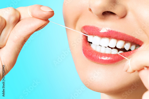 Young beautiful woman is engaged in cleaning teeth. Beautiful smile healthy white teeth. A girl holds a dental floss. The concept of oral hygiene. © Aleksandr Rybalko
