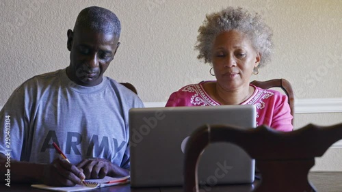 Retired Black military man and wife researching benefits on laptop