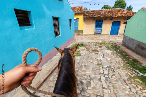 Fototapeta Naklejka Na Ścianę i Meble -  Riding on top of a Horse in the streets of a small Cuban Town during a vibrant sunny day. Taken in Trinidad, Cuba.