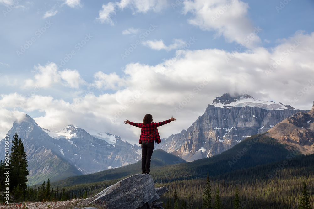 Girl enjoying the beautiful scenery of the Canadian Rockies during a cloudy and sunny summer day. Taken on Icefields Parkway, Banff, Alberta, Canada.