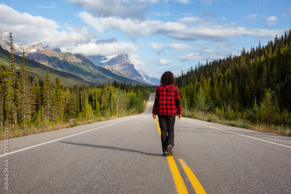 Girl walking down a scenic road in the Canadian Rockies during a vibrant summer morning. Taken in Icefields Parkway, Banff National Park, Alberta, Canada. Girl walking down a scenic road in the Canadian Rockies during a vibrant summer morning. Taken in Icefields Parkway, Banff National Park, Alberta, Canada.