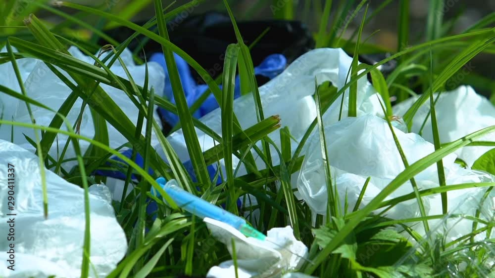 Syringe lying on landfill in green grass, dangerous medical disposables