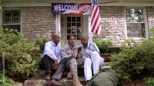 Father and military son watching cell phone on front stoop