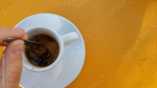 Top view of hand stirring sugar in coffee photo