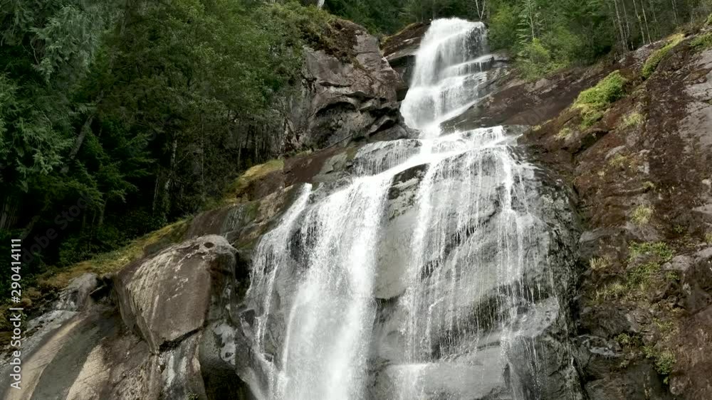 Handheld medium slow motion shot of the water flowing down a waterfall from a rocky mountain Handheld medium slow motion shot of the water flowing down a waterfall from a rocky mountain